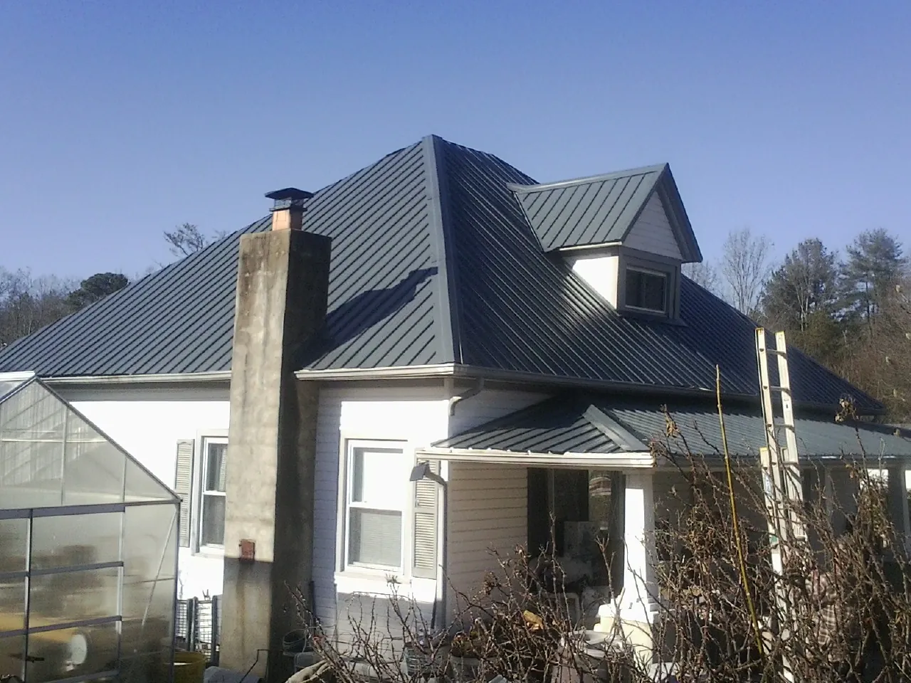 Dark blue standing seam metal roof on a white farmhouse with dormer — Slate & Tile Roof Repair by Roofing Brothers in East Walpole