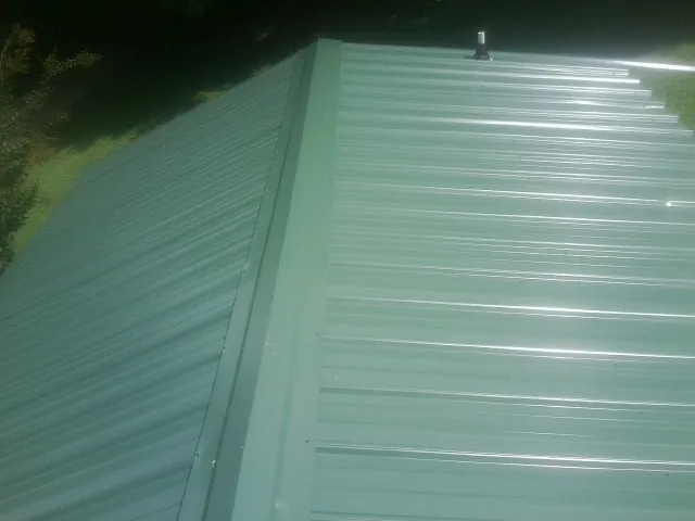 New green metal panels meeting at the ridge of a roof — Flat Roof Repair work by our crew in East Walpole