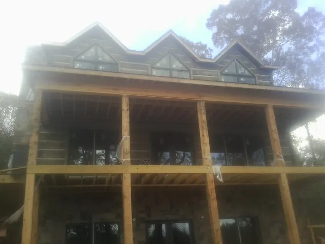 Dormers and porch framing on a large log home under construction — Roof Coating work by our crew in East Walpole