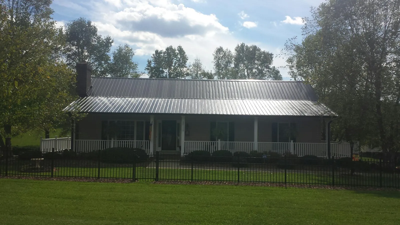 Gray metal roof on a brick ranch with a full width front porch — Gutter Guard Installation work by our crew in East Walpole