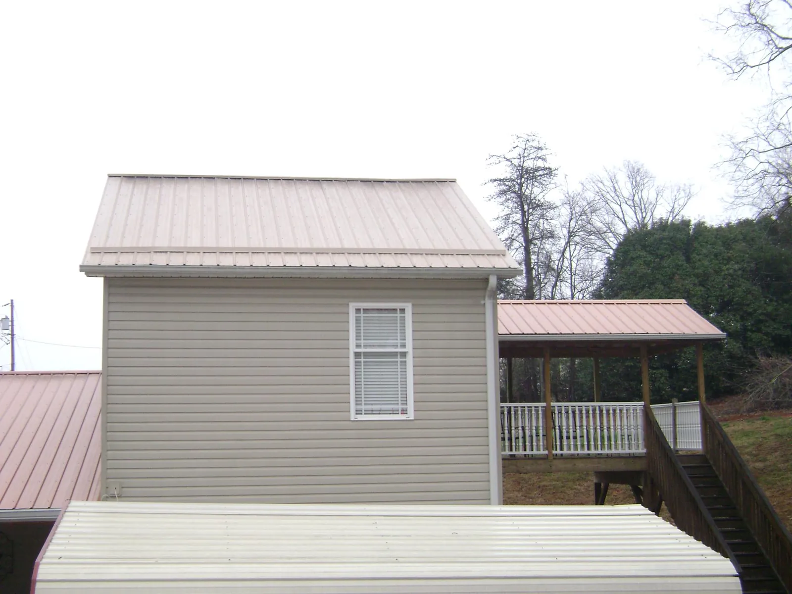 Tan metal roofs on a two story addition and attached porch, from a Roof Replacement job in East Walpole